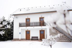 a white house with wooden doors and a balcony at Apartmán Tady 67 in Dolní Moravice