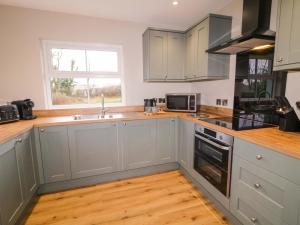 a kitchen with white cabinets and a sink and a window at Annies Farm Cottage in Derry Londonderry