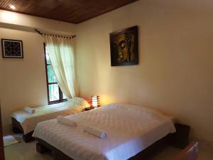 1 dormitorio con 2 camas y ventana en Villa Thakhek, en Thakhek
