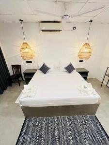 a large white bed in a room with two lights at La Manga Mirissa in Mirissa +24 photos