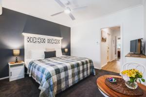 a bedroom with a bed and a table and a tv at Rosewood Guesthouse in Margaret River Town