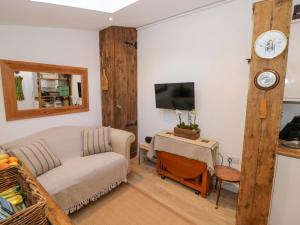 a living room with a couch and a clock on the wall at Tucked Away in Evesham