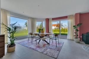 a dining room with a table and chairs and large windows at 't Vennehuys - vakantiehuis nabij Bokrijk in Genk