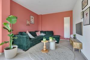 a living room with a green couch and pink walls at 't Vennehuys - vakantiehuis nabij Bokrijk in Genk