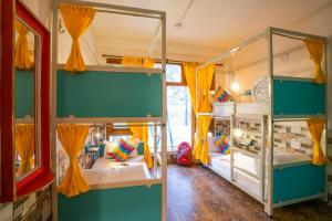 two bunk beds in a room with yellow curtains at goSTOPS Kasol in Kasol