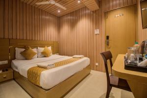 a hotel room with a bed and a desk with a table at Hotel Malad Inn opposite Malad Railway Station in Mumbai