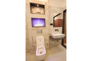 a bathroom with a toilet and a tv on the wall at Hotel Anmol One in Indore