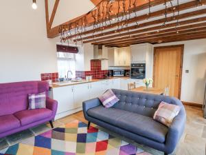 a living room with two purple couches and a kitchen at Chestnut Barn in Whitby