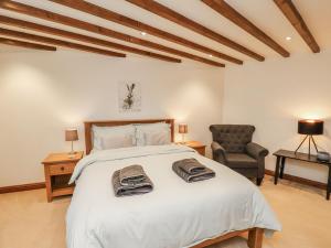 a bedroom with a large white bed and a chair at Chestnut Barn in Whitby