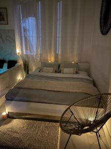 a bedroom with a large bed and a chair at Love White Room Privée avec Spa privatif in Tourcoing