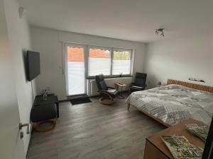 a bedroom with a bed and two chairs and two windows at Ferienwohnung Käthe in Rhauderfehn