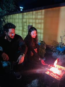 a man and a woman sitting next to a fire at Patkai Backpackers Hostel in Guwahati