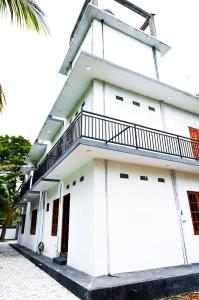 a white building with a balcony at Rika Guest House in Kokkuvil East