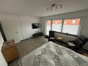 a bedroom with a bed and two chairs and a tv at Ferienwohnung Käthe in Rhauderfehn +2 photos