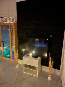 a living room with a tv and a candle on a table at Love White Room Privée avec Spa privatif in Tourcoing +1 photo