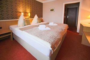 a hotel room with a large bed with two towels on it at Hotel-Restaurant Alter Krug Kallinchen in Kallinchen