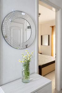 a vase with yellow flowers on a table with a mirror at Rona Vista Suites amazing seaview 3 in Polychrono
