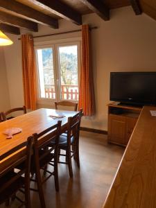 a dining room with a table and a flat screen tv at Sous l'Alpette en Chartreuse in Saint-Pierre-dʼEntremont