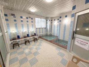 a bathroom with a tub and a sink and mirrors at Hotel Tetora HonHachinohe in Hachinohe