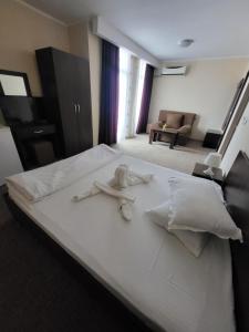 a bedroom with a white bed with towels on it at Vila KM 0 in Neptun