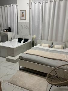 a bedroom with a bed and a bathtub and a bed and a tub at Love White Room Privée avec Spa privatif in Tourcoing