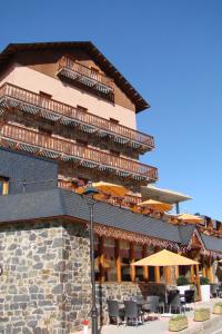 un bâtiment avec des chaises et des parasols en face de celui-ci dans l'établissement Hotel Solineu, à La Molina