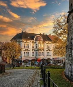 a large white building with a sunset in the background at Zamkowa Apart in Cieszyn