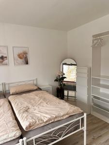a white bedroom with a bed and a mirror at Schöne Ferienwohnung mit Waldblick in Dillenburg in Dillenburg