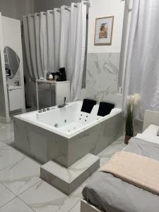 a white bathroom with a tub and a bed at Love White Room Privée avec Spa privatif in Tourcoing