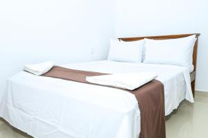 a bedroom with two beds with white sheets and pillows at Rika Guest House in Kokkuvil East