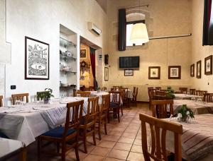 a restaurant with long tables and chairs and a television at Hotel Il Barocco in Ragusa