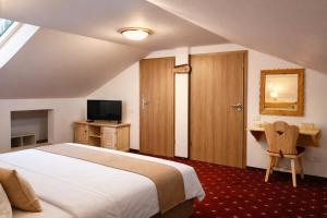 a bedroom with a bed and a desk and a television at Vila Belcin Spa&Retreat in Buşteni