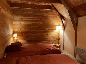 a bedroom with a wooden wall with two beds at Grange Mary in Le Falgoux +15 photos