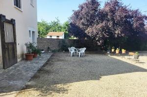 a patio with two white chairs and a table at L'Etalon, maison dans corps de ferme in Chailly-sur-Armançon