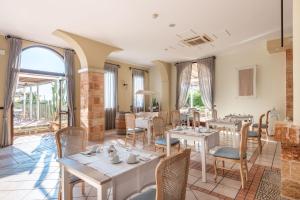 a restaurant with tables and chairs and windows at Hotel Montecallini - Adult Only 14 in Leuca