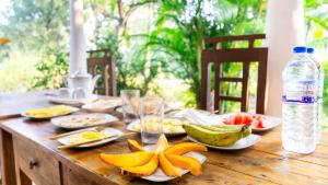 a wooden table with plates of fruit and a bottle of water at Sigiri Binara Villa in Sigiriya +57 photos