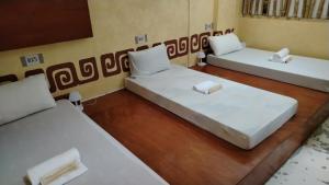 three beds in a room with white sheets at Palawan Coliving - Palawan Coworking in Puerto Princesa City +27 photos