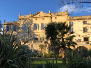 a large building with a palm tree in front of it at Château de Collias - Maison de Vacances in Collias