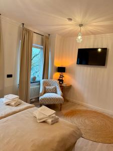 a bedroom with two beds and a chair and a television at Residenz am Pferdemarkt - exklusives Wohnen im Herzen Ostfrieslands - stillvoll & luxuriös in Aurich