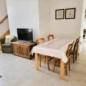 a dining table and chairs in a living room with a television at L'Etalon, maison dans corps de ferme in Chailly-sur-Armançon
