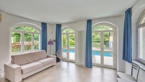 a living room with a couch and windows and a pool at spiaggia uno pool side apartment in Bellagio