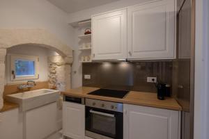 a kitchen with white cabinets and a sink and a stove at Rimondi Boutique Hotel - Small Luxury Hotels of the World in Rethymno