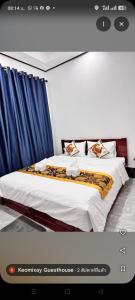 a bedroom with a large bed with blue curtains at Keomisay in Nongkhiaw