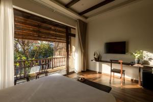 a bedroom with a bed and a desk and a balcony at ZenHome by M2 in Hoi An