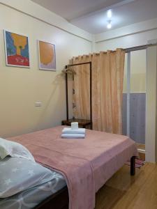 a bedroom with a bed with a pink blanket at Cardo Rooms 2 minutes walk from the beach in General Luna