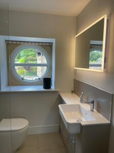 a bathroom with a sink and a toilet and a window at Cumberwell Cottages-Dash Corner in South Wraxall +32 photos
