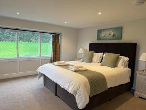 a bedroom with a large bed with a large window at Cumberwell Cottages-Dash Corner in South Wraxall