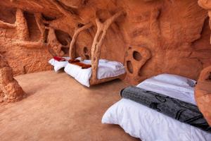 a room with three beds in a rock wall at Wadi Rum Cave Camping in Wadi Rum +149 photos
