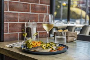 a plate of food on a table with a glass of wine at Campanile PRIME - Troyes Nord Barberey in Troyes