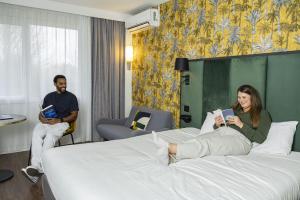 a woman laying on a bed in a hotel room at Campanile PRIME - Troyes Nord Barberey in Troyes
